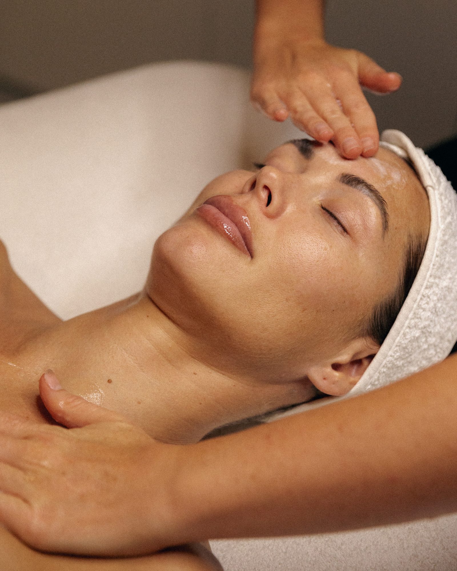 Hands at work during a signature facial in the Üesthetics treatment room